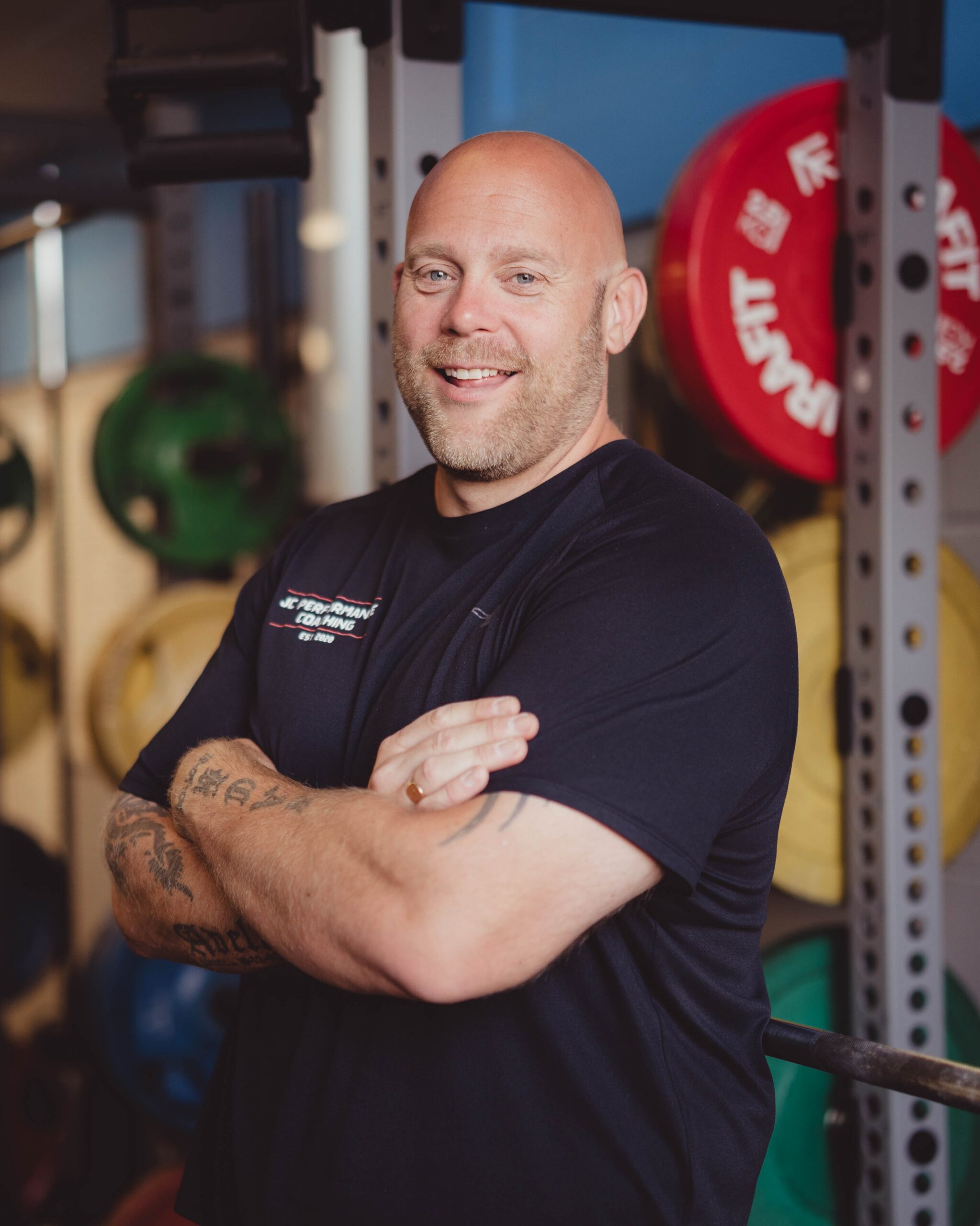 JC Performance Coaching coach posing in front of weight plates in Chelmsford